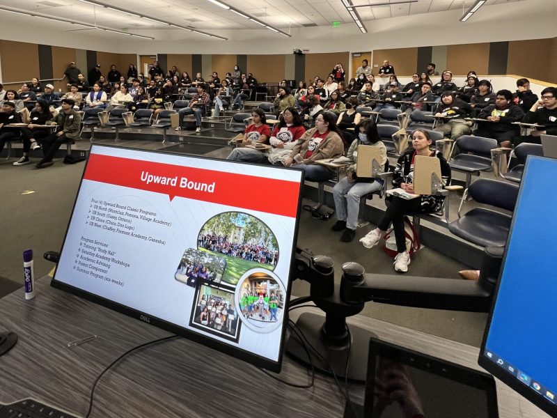 Group of students in lecture hall with a computer presenting in the front.